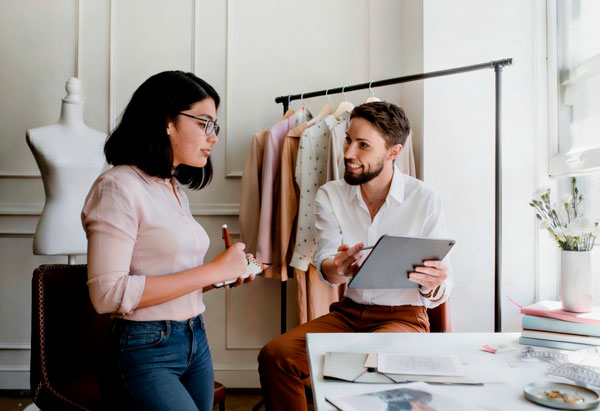 Homem e mulher em uma sessão de trabalho de personal stylist, sentados com o homem apresentando o trabalho