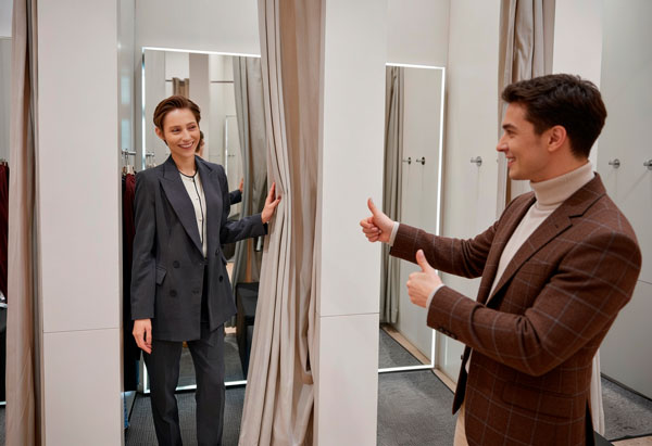 Mulher provando roupa que o personal stylist escolheu para ver como a roupa trabalha no corpo, ambos felizes com a escola do look